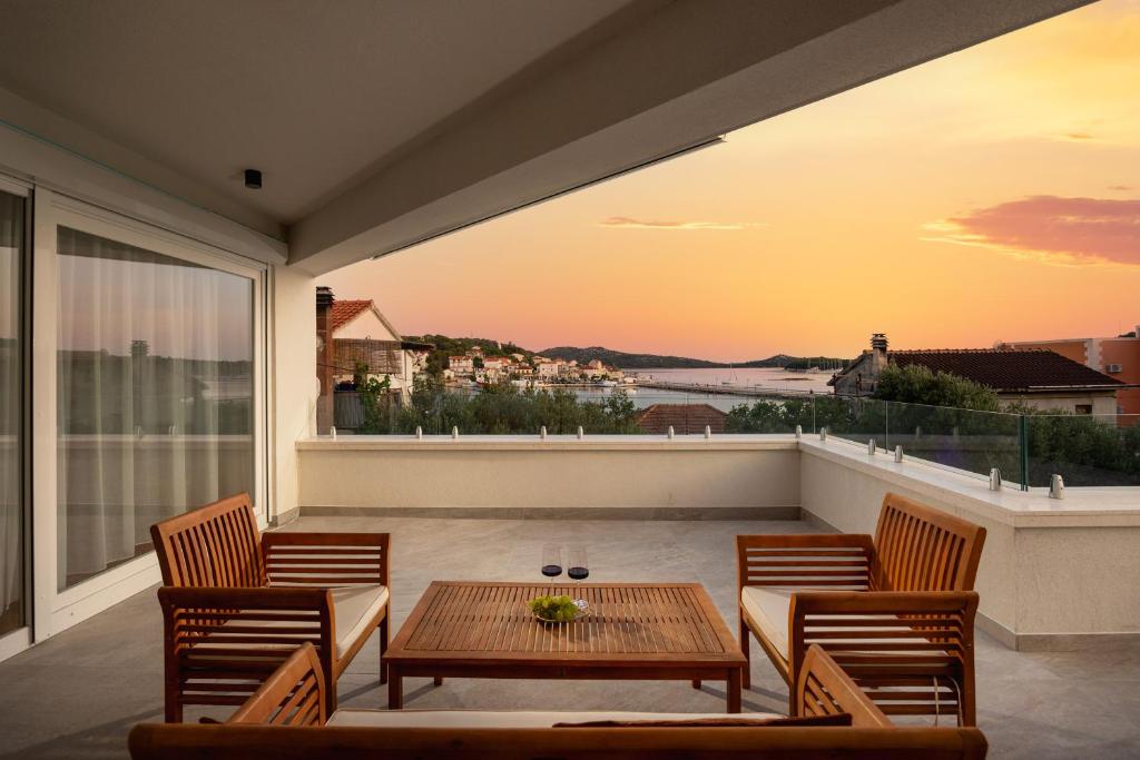 Covered terrace with wooden lounge furniture at sunset over the bay